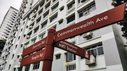 Street signposts pointing to Commonwealth Ave, Dawson Rd, Tanglin Rd and Queenstown MRT Station in front of HDB flats