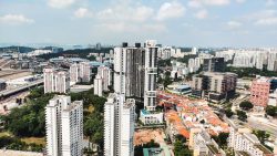 High-rise residential blocks and low-rise terraced houses among greenery and industrial buildings by the sea