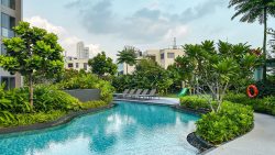 Swimming pool at Clement Canopy with sun loungers, greenery and a children's playground in the background