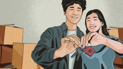 Couple smiling while holding house-shaped keychain and keys with cardboard boxes in background