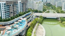 Watertown residential blocks beside a children’s water play area and a river with a pedestrian bridge