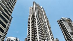 High-rise apartment blocks with balconies and black window panels under a clear blue sky