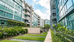 The Sixth Avenue Residences apartment blocks with landscaped gardens, water features and glass balconies under blue sky