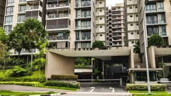 Entrance gate and drop-off point of Treasure Crest EC with tall residential blocks and greenery surrounding it