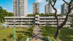 Multi-storey car park with residential apartment blocks and green trees in the background