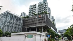 KINEX commercial and residential building with street and vehicles in foreground under cloudy sky
