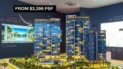 Scale model of apartment blocks with price information and promotional images in sales office interior