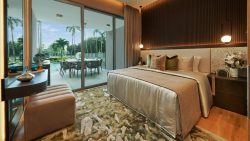 Bedroom with a bed, bedside tables, hanging pendant lights, and glass doors leading to an outdoor dining area