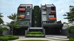 Pollen Collection II residential blocks with dark facades, orange balconies, greenery-covered central section, and landscaped grounds
