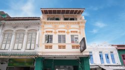 Three-storey shop houses with intricate mouldings, louvered windows and a blank hanging signboard