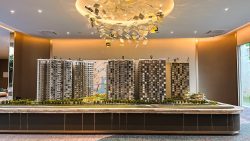 Grand Dunman scale model with five residential blocks, greenery, and a decorative ceiling light installation above