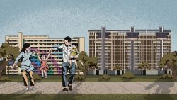 Family with two young children walking and playing in front of two apartment blocks and trees