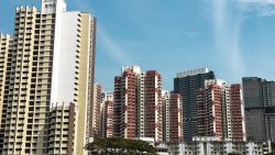 Cluster of high-rise residential blocks with beige and red facades under a clear blue sky