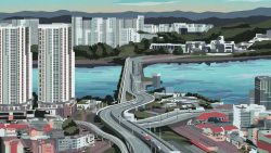 High-rise residential blocks near a river with a highway and hills in the background