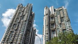 Two tall Rivergate apartment towers with balconies under a partly cloudy blue sky