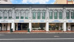 Row of restored two-storey shophouses with decorative arches and white shutters along a city street
