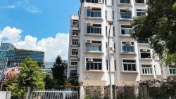 White multi-storey residential block at 40 Lloyd Road with aircon units, trees and a streetlamp in front