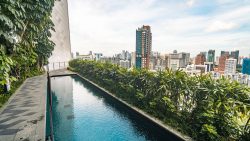 The Scotts Tower rooftop pool beside a walkway with greenery and city skyline in the background
