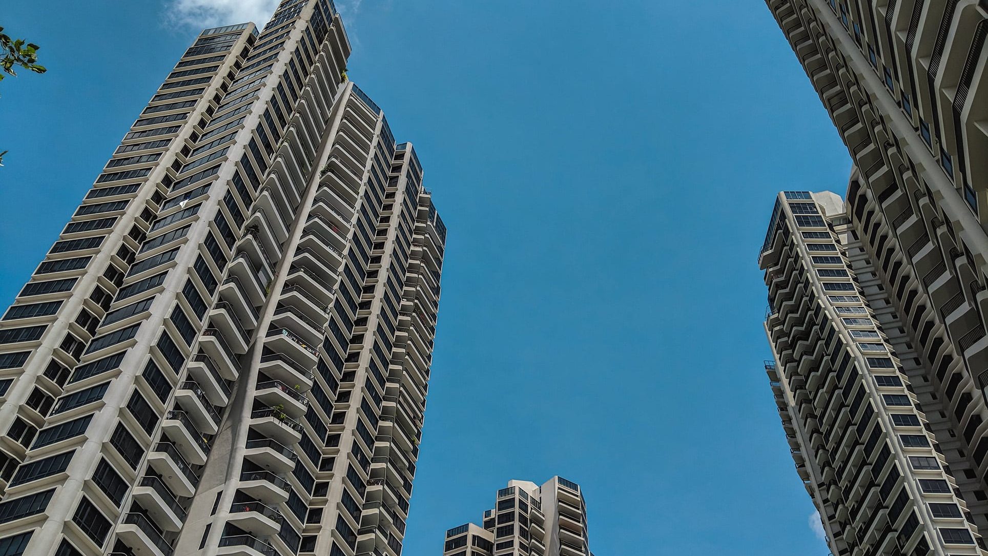 Tall D Leedon apartment blocks with balconies under a clear blue sky