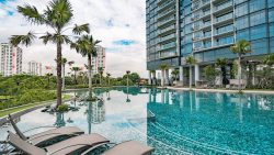 Twin VEW swimming pool with palm trees, poolside lounges, and high-rise apartment block facade