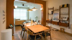 Dining area with wooden table and mixed chairs, pendant lights, open archway to living room with sofa and large window