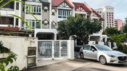 Three-storey terrace houses with pitched roofs and a silver car parked in front of a gate