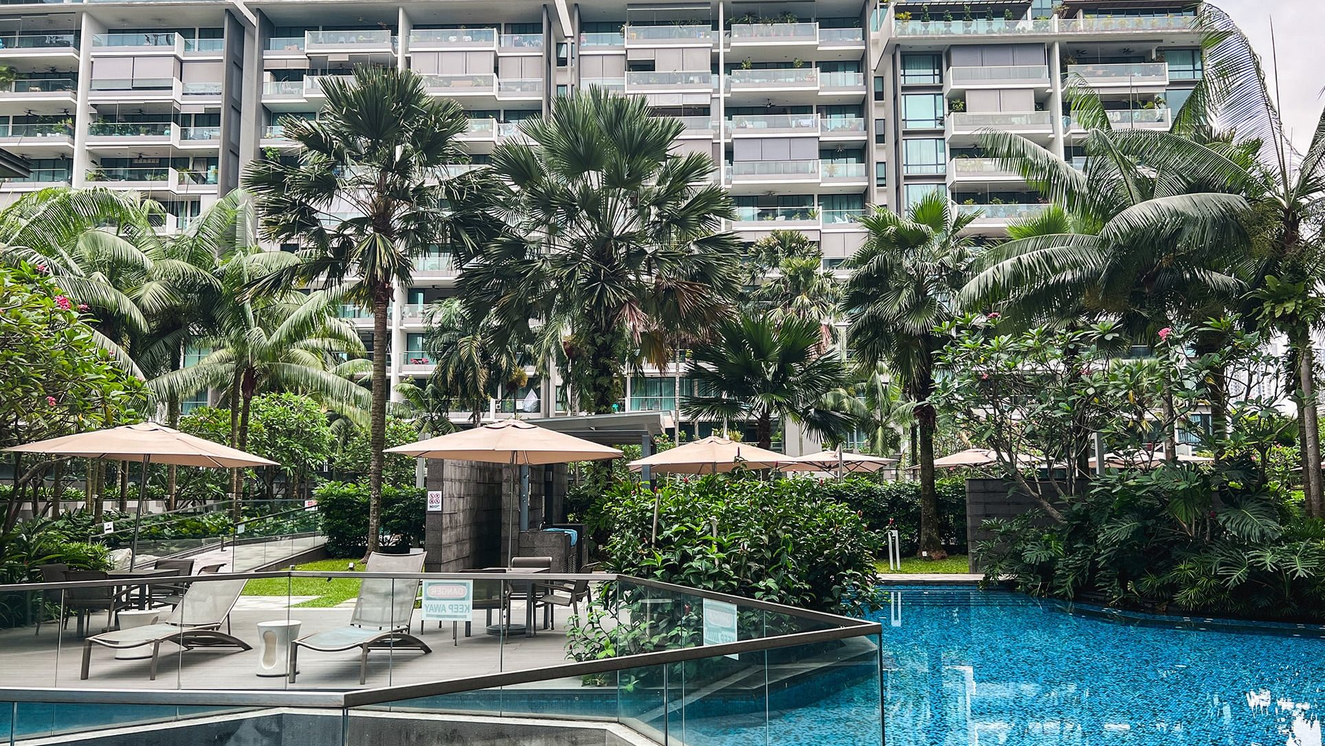 Parvis apartment blocks with outdoor pool, sun loungers, umbrellas and tropical landscaping