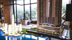 Scaled architectural model of multiple high-rise apartment blocks with a waterfront and greenery indoors