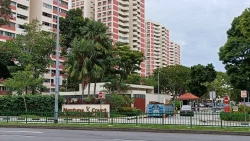 Neptune Court residential blocks with pink and white facade behind trees and entrance gate with guardhouse