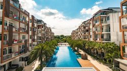 Parc Rosewood apartment blocks flanking a long swimming pool with palm trees and clear blue sky