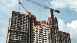 High-rise residential blocks under construction with cranes and orange safety netting on upper floors
