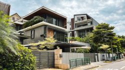 Modern multi-storey houses with large windows and greenery surrounding a quiet street corner