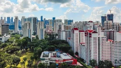 High-rise residential blocks with red roofs near a large green park under a partly cloudy sky
