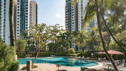 Parc Oasis apartment blocks behind a swimming pool and poolside seating surrounded by trees and greenery