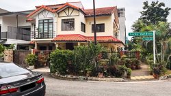 Two-storey corner terrace house with tiled roof, fenced garden, and a street sign reading Lucky Gardens