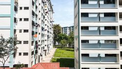 Public housing blocks with clothes hanging outside windows and a green lawn courtyard below