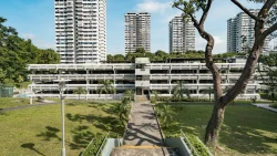 White multi-storey carpark with residential blocks behind and tropical trees in front under a blue sky