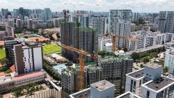 Construction site with cranes among high-rise residential blocks and green spaces in an urban area