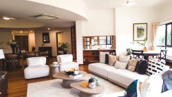 Living room with cream sofa, armchairs, round coffee tables, dining table and wood flooring