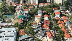 Cluster of landed houses with red-tiled roofs and nearby residential blocks surrounding tennis courts