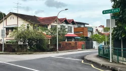Corner terrace house with red tiled roof and greenery by Binjai Park street signs