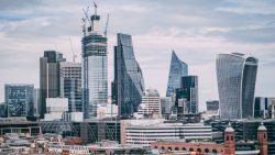 Cluster of modern office skyscrapers with cranes amid partly cloudy sky in city centre