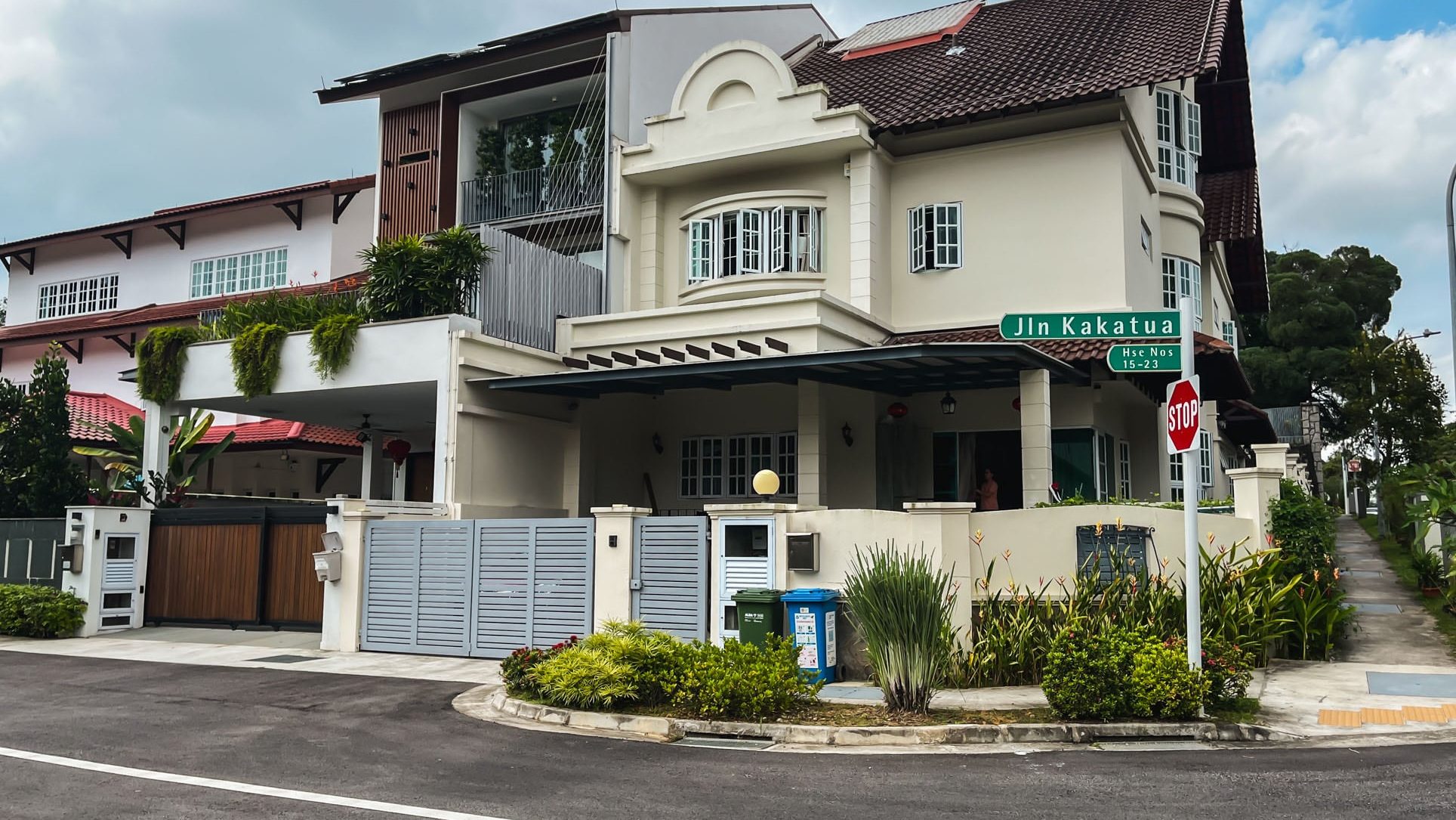Corner terrace house with gated driveway and greenery along the sidewalk on Jalan Kakatua street