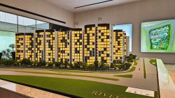 Rivelle EC architectural model with lit apartment blocks and greenery on a display table with site plan on wall