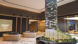 Scale model of Newport Residences tower and low-rise buildings displayed in a showroom with chairs and marble flooring