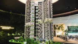 Detailed architectural model of One Pearl Bank residential blocks with greenery and indoor showroom seating area