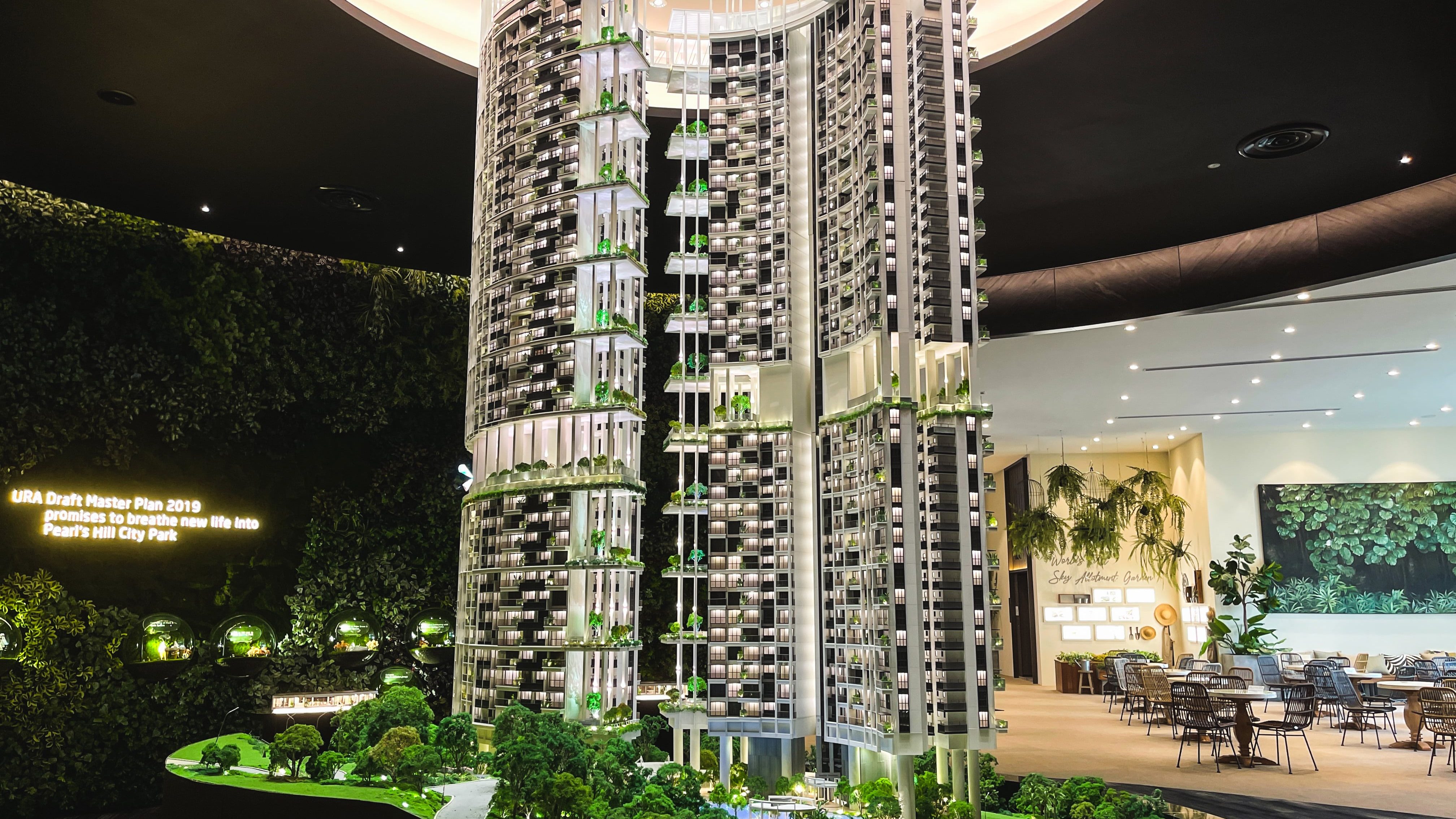 Detailed architectural model of One Pearl Bank residential blocks with greenery and indoor showroom seating area