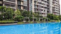 Residential apartment blocks with balconies beside a swimming pool and landscaped gardens with cabanas