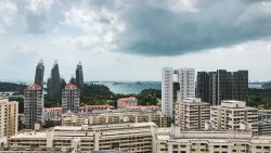 Residential blocks near green spaces and the sea with ships under a cloudy sky