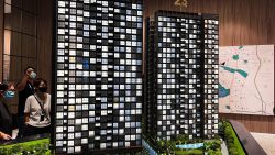 Scale model of Amo Residence residential blocks with people viewing it and a location map on the wall